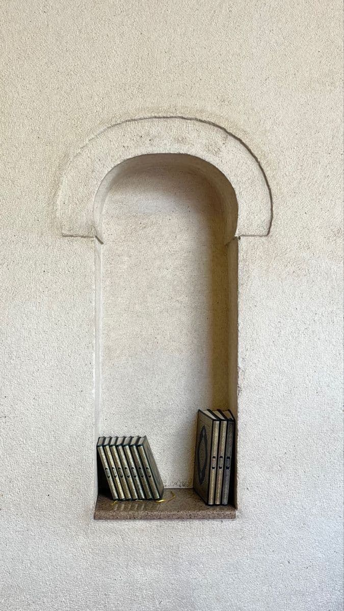 Qur’an volumes resting on a shelf within an arched wall niche