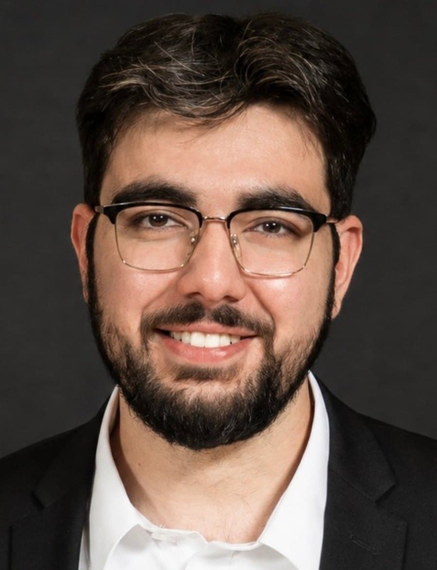 Ustadh Zaid Yousef, smiling, in glasses, a dark jacket and a white shirt